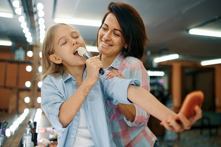 母亲和女儿在化妆沙龙开玩笑妈和小女孩一起玩化妆师快乐的童年迷人家庭玩得开心妈和女儿在化妆沙龙开玩笑图片