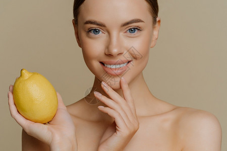 被裁剪的可爱微笑女模特儿皮肤温柔轻地抚摸着脸部拿黄汁柠檬用天然化妆品图片