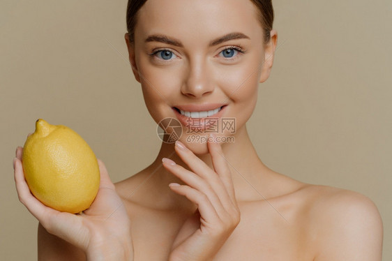 被裁剪的可爱微笑女模特儿皮肤温柔轻地抚摸着脸部拿黄汁柠檬用天然化妆品图片