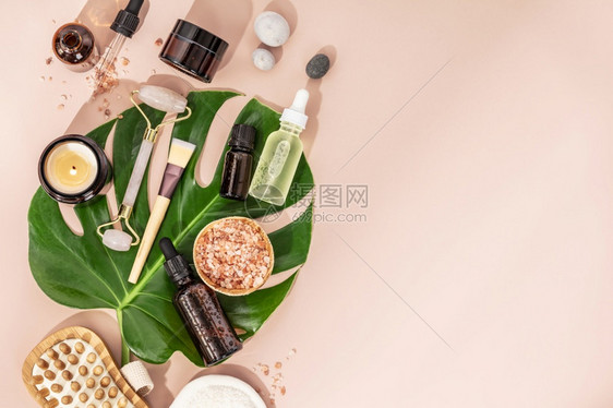 天然SPA化妆品背景含有粉底平板复制空间的几瓶基本油海盐奶刷子按摩机和热带叶的成分图片