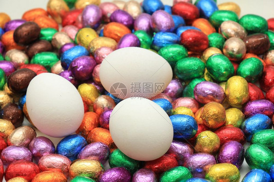 鸡蛋在一堆多彩的包着巧克力蛋上图片