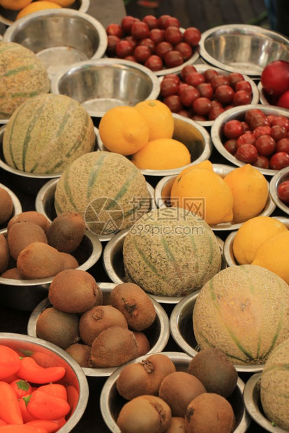 在小金属碗中展示的市场摊位基威瓜和柠檬上的新鲜水果图片