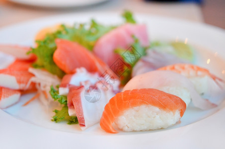 混合寿司和生鱼在白盘上供养图片