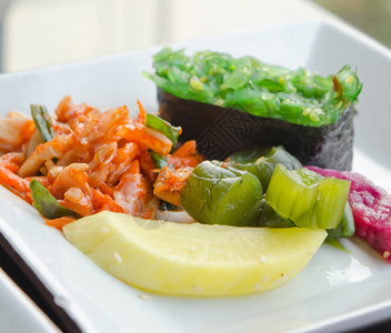 Kimchi和泡菜蔬Chuka海藻在白盘上撒沙子图片