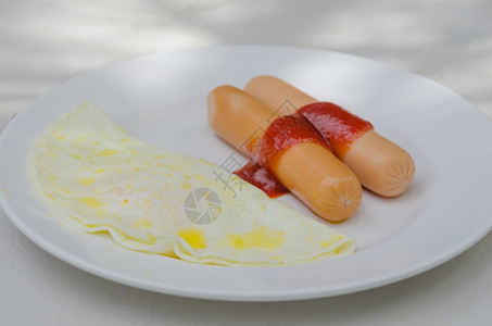 早餐香肠加酱汁和煎蛋在盘子上图片