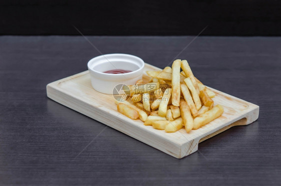 传统薯条配番茄酱的木板上图片