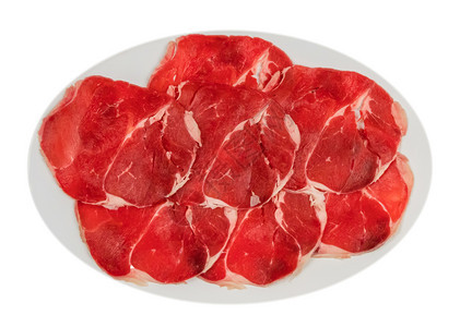 盘子上的生牛肉片白色背景的盘子上一些生牛肉片的顶端视图图片