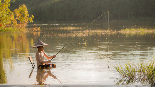 亚小男孩在湖里钓鱼图片