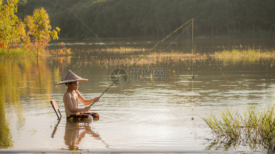 亚小男孩在湖里钓鱼图片