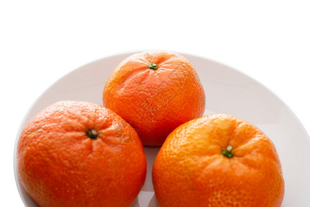 白色的盘子上背景三个新鲜多汁的橘子侧面视图图片