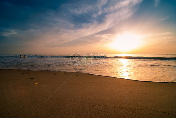 日落和沙滩水面上有冲浪者的脚影图片