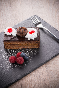 一块巧克力蛋糕果浆在黑板盘上图片