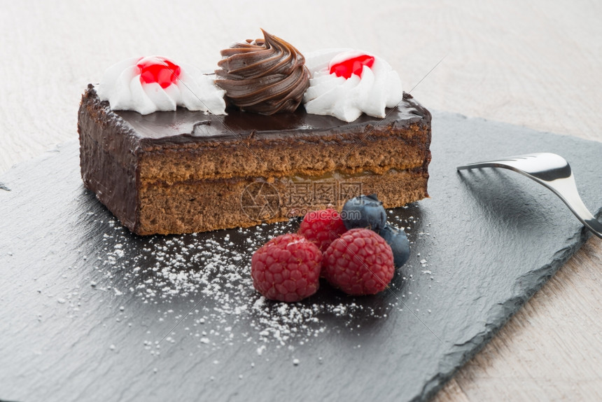 一块巧克力蛋糕果浆在黑板盘上图片