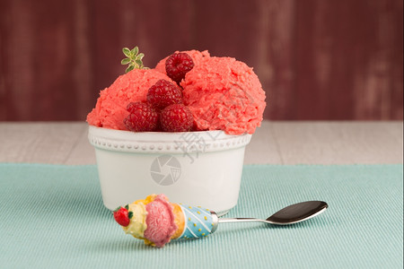 红水果冰淇淋和勺子放在桌背地图片