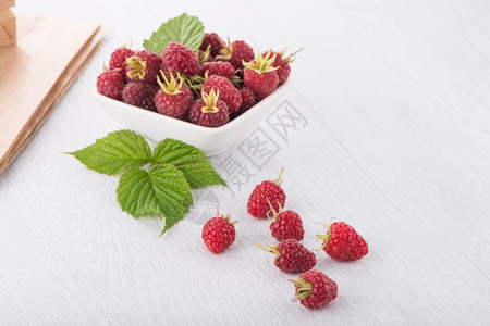 新鲜的草莓放在木制桌上的白碗里图片