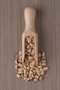 棕色黑咖啡背景的白豆子木制勺顶端视图图片