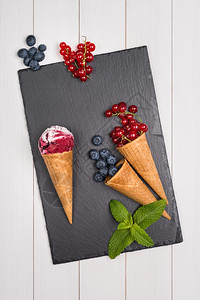 红水果冰淇淋甜筒放在木制桌上图片