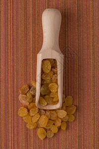 红色黑乙烯基背景的金葡萄干木制勺的顶端视图图片