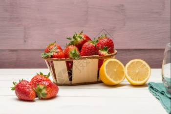 小篮子里的草莓和木制桌上的柠檬图片
