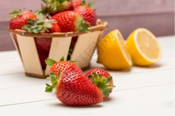 小篮子里的草莓和木制桌上的柠檬图片