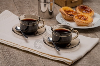 帕斯蒂德纳塔PastesdeNata或葡萄牙的CustardTarts木制桌上有黑咖啡图片