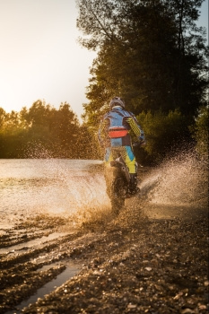 在美丽的日落面前穿越水和泥土地带的内骑手图片