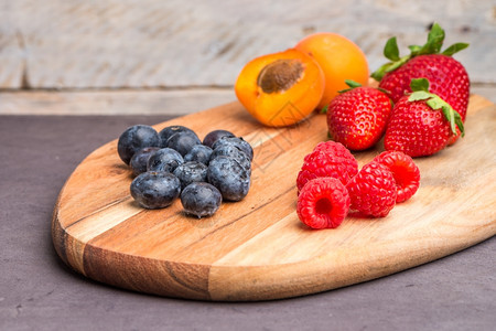 含有新鲜机水果和浆的木板草莓黑和蓝杏仁桃健康点心图片