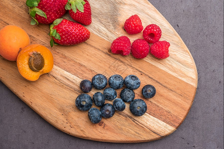 含有新鲜机水果和浆的木板草莓黑和蓝杏仁桃健康点心图片