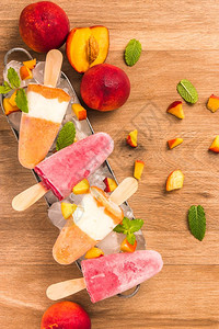木桌上自制的草莓和桃子冰棒图片