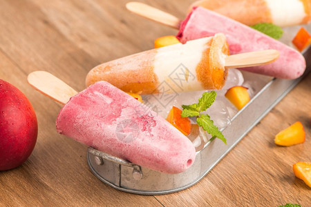 木桌上自制的草莓和桃子冰棒图片
