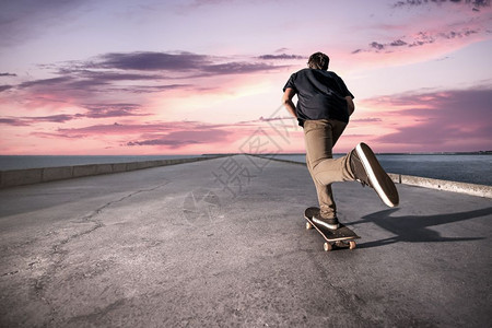 在日落时滑板机沿港口推着水泥路行驶图片