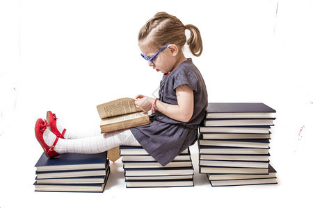 金发可爱的小女孩阅读百科全书在块上的百科全白色背景图片