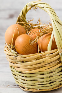 天然棕蛋在白木本底的草篮里图片