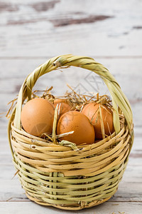 天然棕蛋在白木本底的草篮里图片