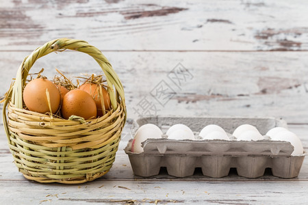 草篮中的天然棕蛋和现代纸板中的白蛋图片
