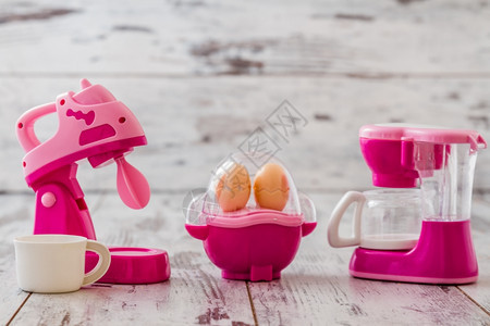 白色木制桌上的粉塑料厨房玩具机图片