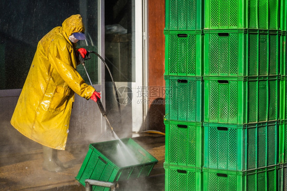 在黄色安全防护设备中打扫绿箱的工人图片
