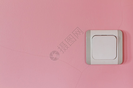 粉红色墙上的旧白灰电开关图片