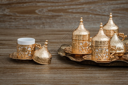 传统金色咖啡杯套在棕木背景的托盘中图片