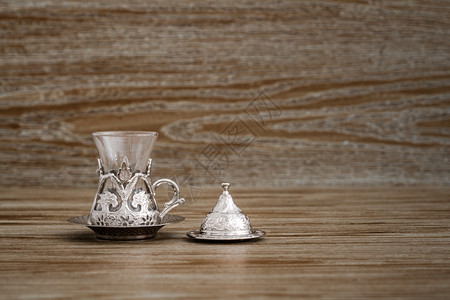 传统银色咖啡杯套在棕木背景的盘子上图片