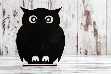 用猫头鹰形状在白木背景上写作的装饰黑白板图片