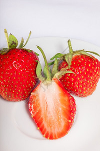 盘子上一半的成熟多汁草莓满两片浆果图片