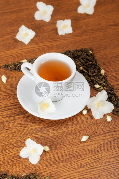 白色杯子和茶碟木制桌上有茉莉花背景图片