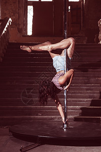 高空舞者美丽的黑发女在地下背景的柱子上跳舞背景