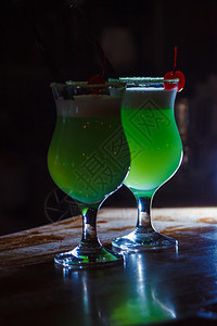 一个美丽的绿色鸡尾酒里面有白泡沫和樱桃在高处的玻璃杯里图片