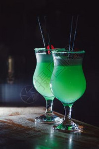 一个美丽的绿色鸡尾酒里面有白泡沫和樱桃在高处的玻璃杯里图片