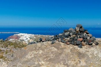 圣托里尼岛Oia村背景上的一座小火山岩石金字塔图片