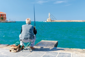 在Chania的码头捕鱼渔民老人在海湾捕鱼图片