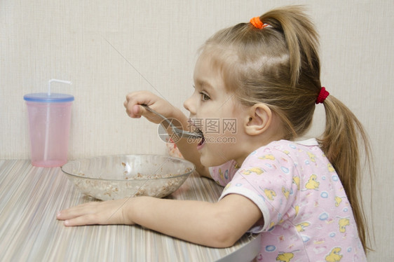小女孩坐在餐桌吃美味的食物图片