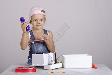 女孩在修理机和玩具微波炉中耍女孩拿着一对钳子看框架高清图片